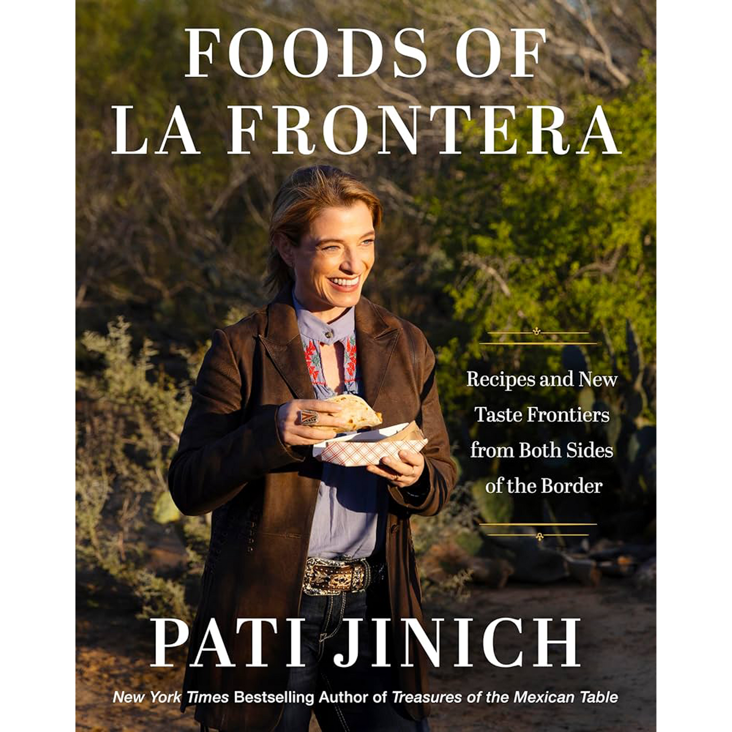 Book cover for 'Foods of La Frontera' by Pati Jinich, featuring a photo of the author outdoors holding a food item, with large white title text and subtitle text on a natural background.