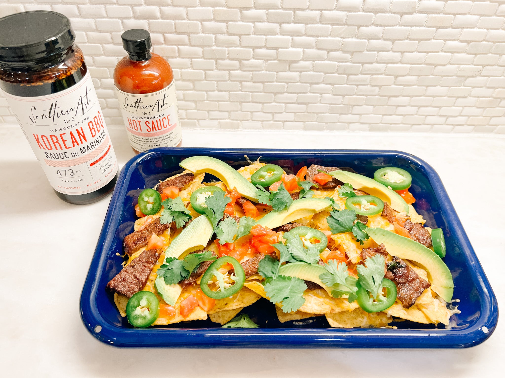 Cheesy Korean Barbecue Nachos with pickled jalapeo, cilantro, and Southern Art Co. hot sauce
