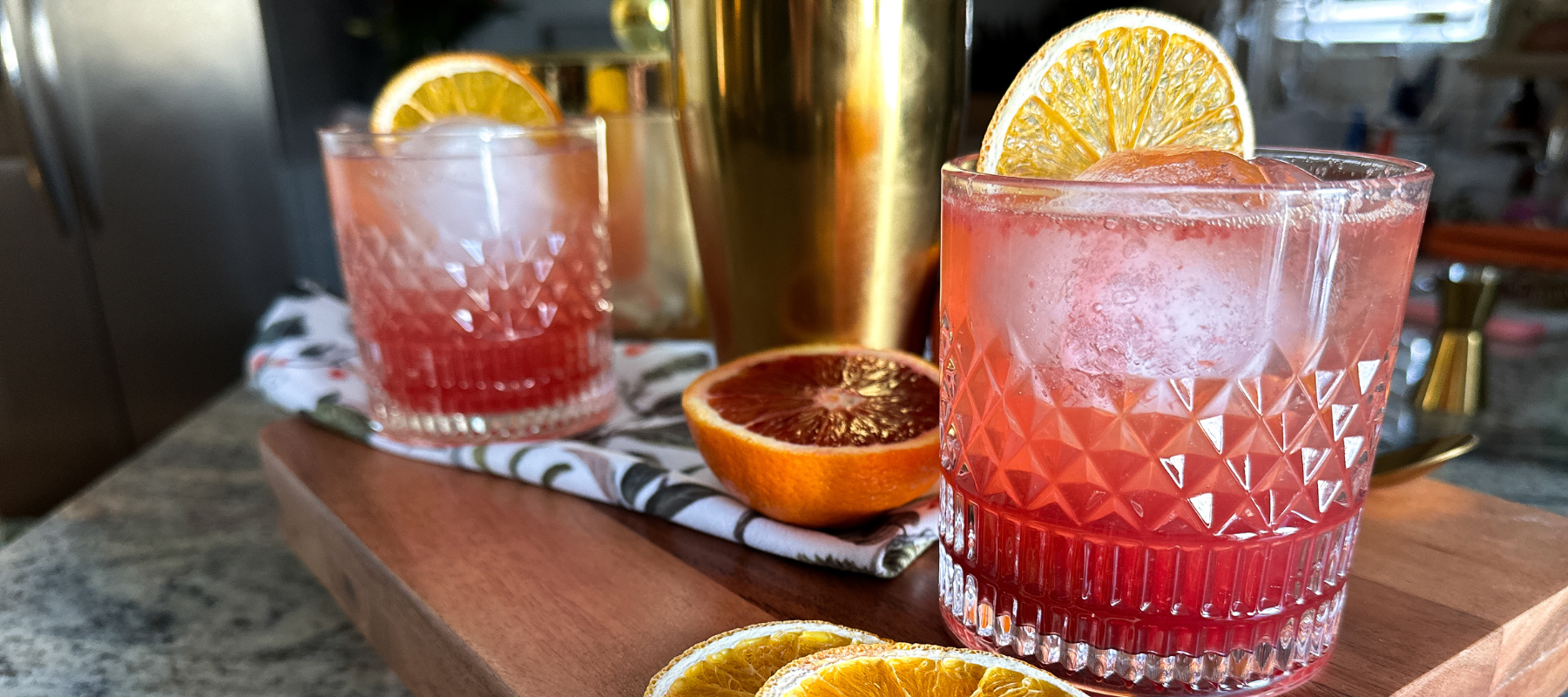 two pink mocktails topped with and surrounded by citrus