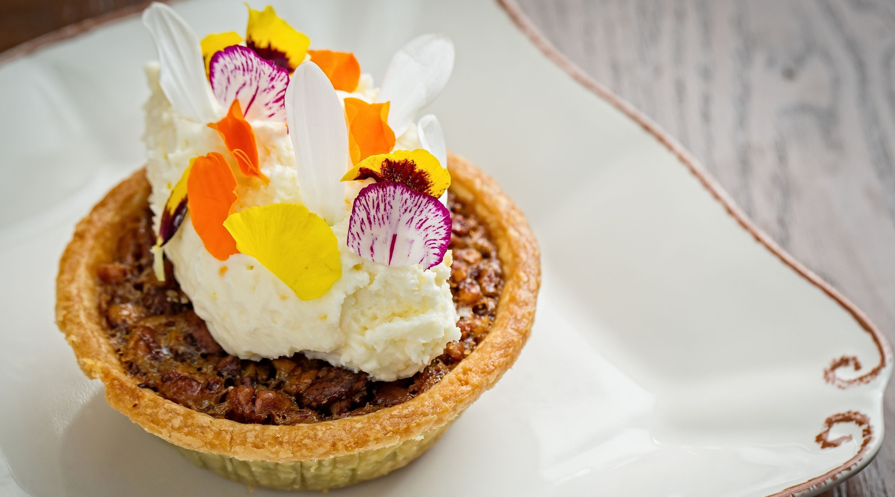 Mini pecan pie topped with ice cream and flower petals