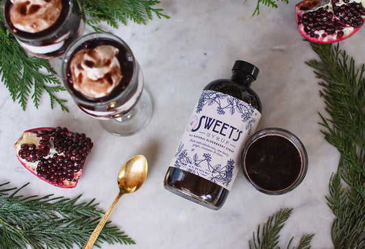 Sweet's Elderberry Syrup on a table with pomegranate seeds