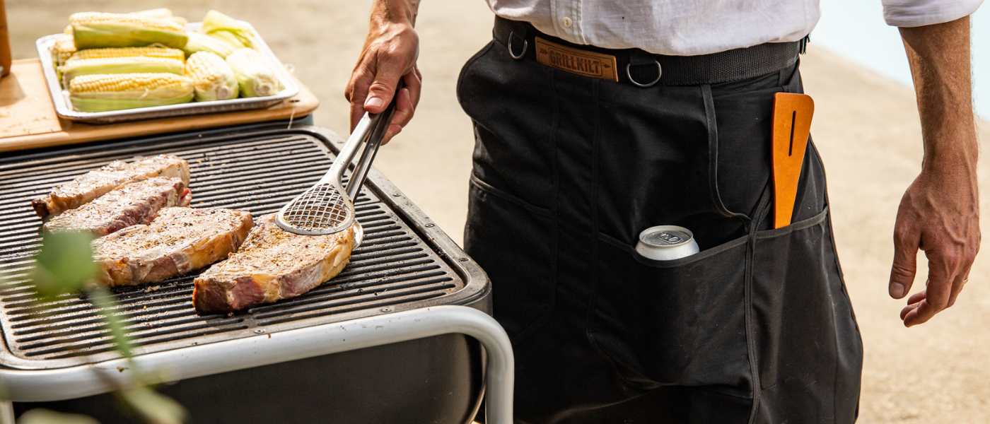 A man wearing the Grill Kilt and flipping pork chops at the grill