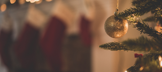 A gold ornament hanging on a Christmas tree