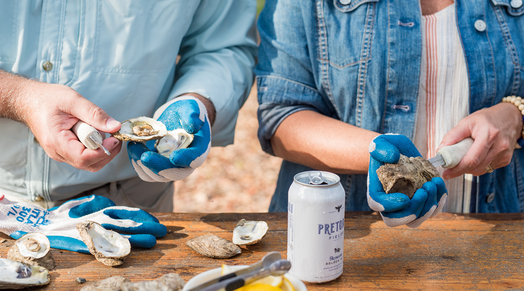 Two people shucking oysters on a table