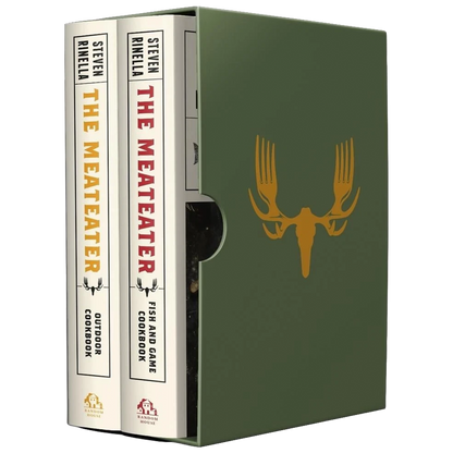 A boxed book set shown on a white background, with two copies of 'The Meateater' standing upright on the left and a matching olive green slipcase on the right featuring a gold deer skull graphic.