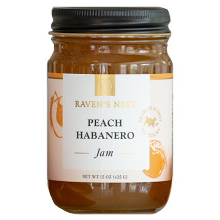 A jar of "Raven's Nest Peach Habanero Jam" with a black lid and a white label featuring the brand logo